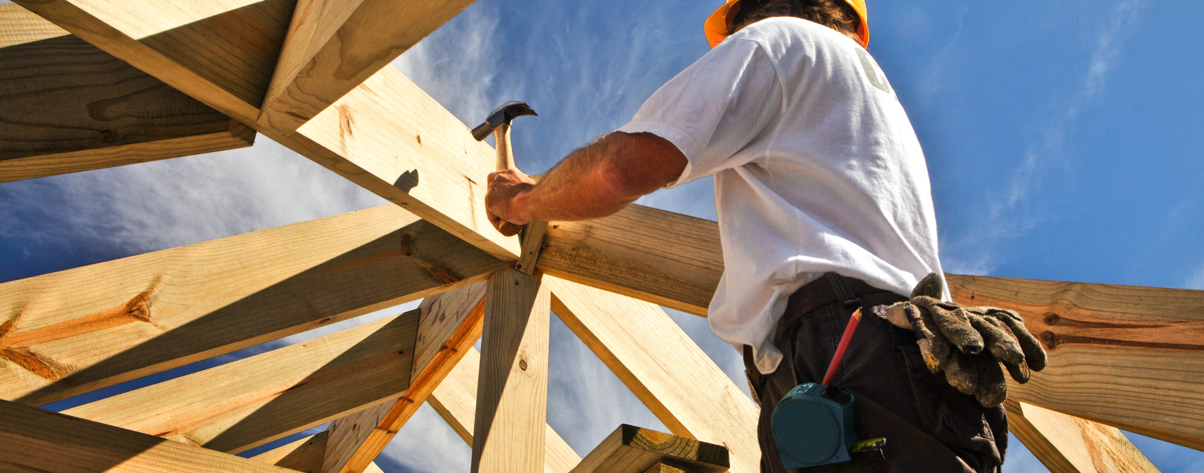 A man holding a hammer and working on the roof of a house.