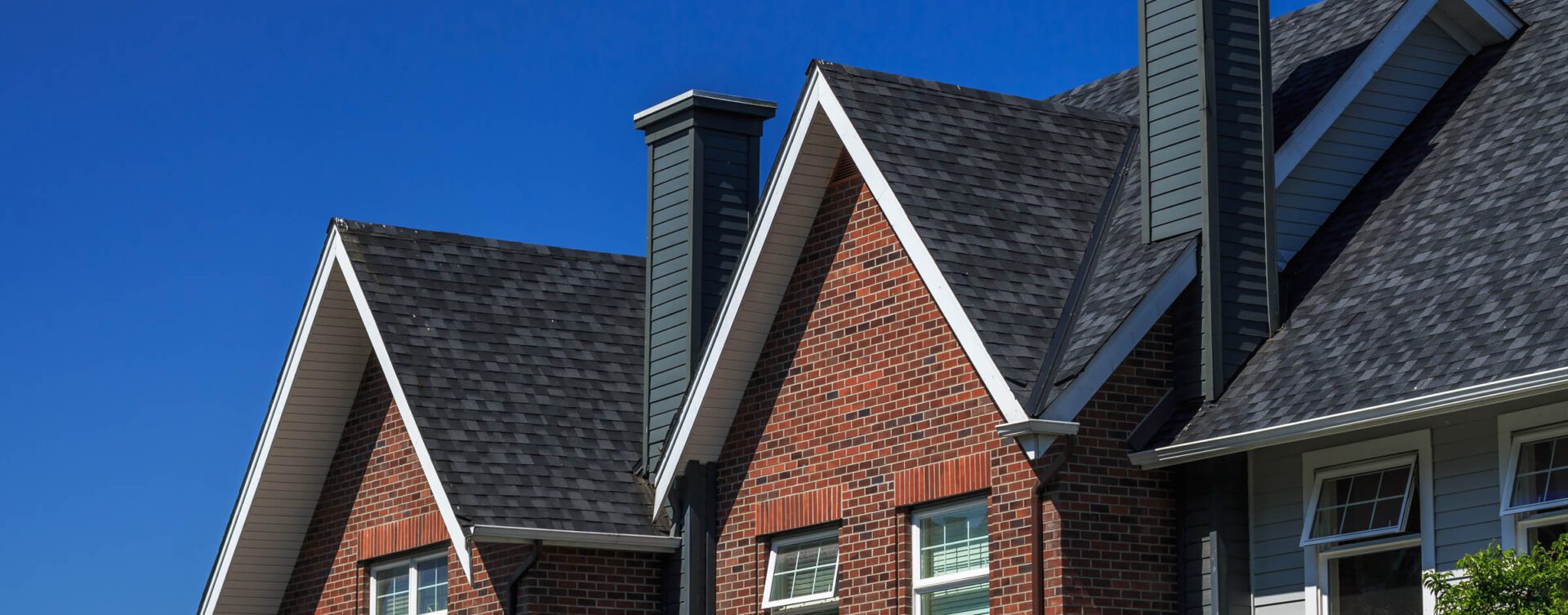 A brick house with a black roof and white trim.